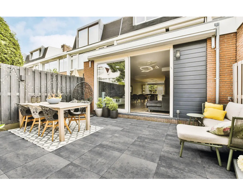 Terras met eettafel, stoelen, loungesessel en stenen tegels