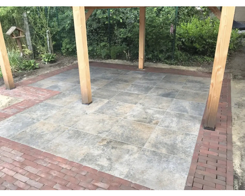 Bestrate patio met houten palen en een stenen rand.