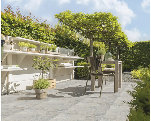 Aangelegde tuin met bestrating, tuintafel, stoelen en plantenrekken