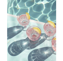 Scène met glazen, drankjes en schijfjes citroen naast een zwembad