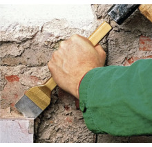 Vakman werkt met een hamer en een beitel aan een muur.