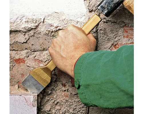 Vakman werkt met een hamer en een beitel aan een muur.