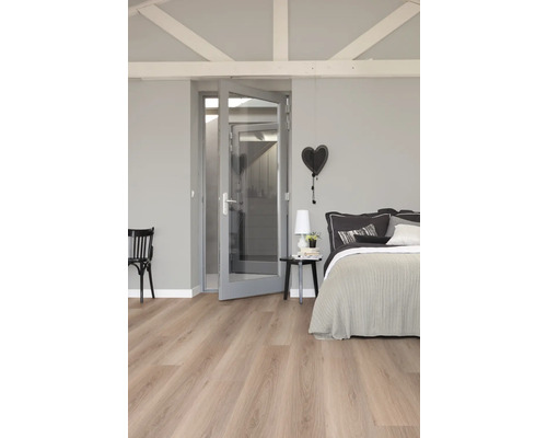 Slaapkamer met bed, nachtkastje, stoel, deur en lichte houten vloer