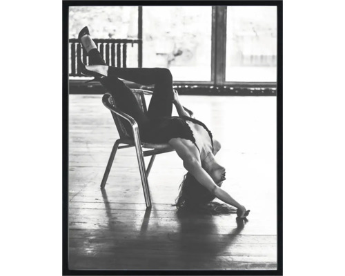 Schilderij met lijst Danseres op stoel zwart wit 40x50 cm Zwart-witfoto van een vrouw die ondersteboven op een stoel zit