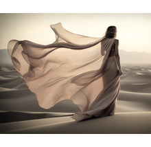 Een vrouw met een wapperende jurk staat in een woestijn.