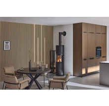 Woonkamer met kachel, eettafel en stoelen voor een houten lambrisering