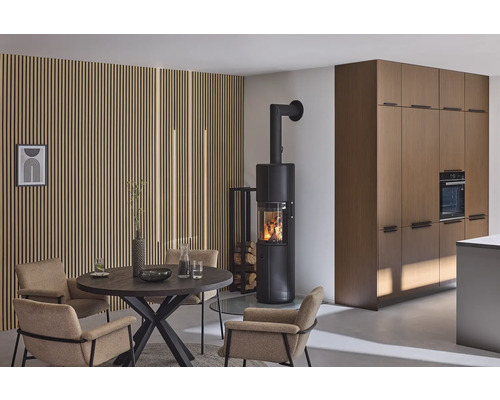 Woonkamer met kachel, eettafel en stoelen voor een houten lambrisering