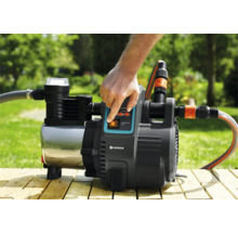 Tuinpomp met schakelaar en aangesloten slangen in gebruik.