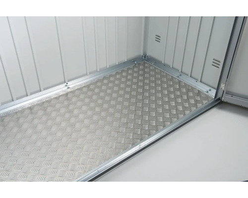 Binnenkant van een gereedschapsschuur met een traanplaatvloer.