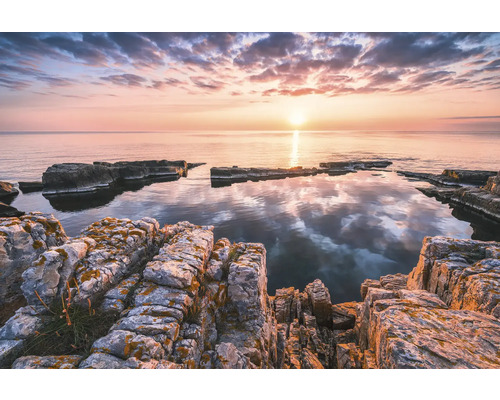 Rotsachtig kustlandschap bij zonsopgang met kalm water