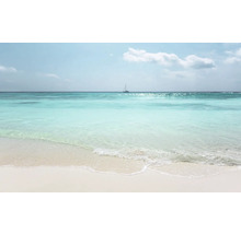 Een helder zandstrand met turquoise zee en een zeilboot aan de horizon