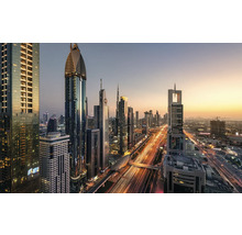 Panoramische opname van de skyline van Dubai met verlichte wolkenkrabbers en wegverkeer in de schemering.