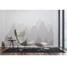 Moderne woonkamer met fauteuil, voetenbank, bijzettafel en behang met bergmotief.