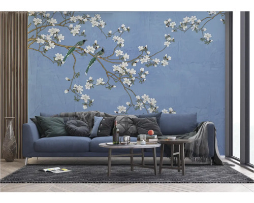 Woonkamer met een blauwe bank voor een behang met vogel- en bloemmotief