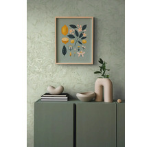 Decoratieve scène met een dressoir, erop een decoratieve schaal, boeken en een vaas, aan de muur een foto met citroenmotieven