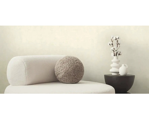 Decoratieve scène met fauteuil, rond kussen, vaas met katoentakken en tafel
