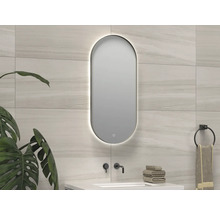 Badkamer met verlichte, ovale spiegel, wastafel en handdoeken