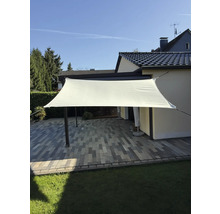 Rechthoekig zonnescherm boven een terras met straatstenen en gazon.