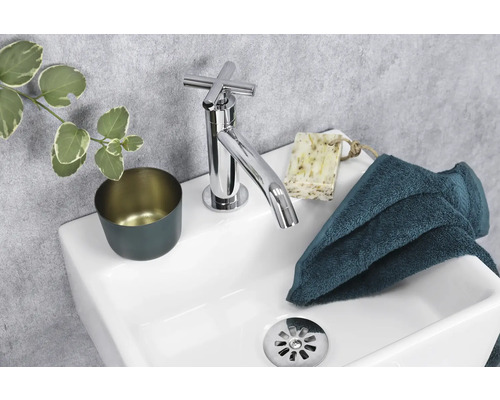 Moderne wastafel met kraan, zeep, handdoek en beker