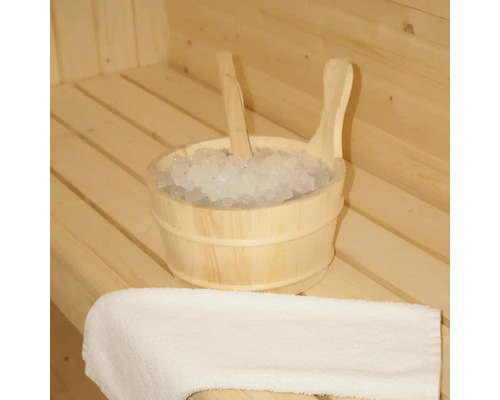 Houten emmer met ijs en een lepel in een sauna, naast een handdoek.