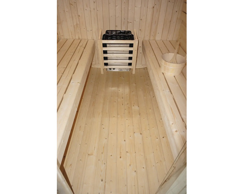 Interieur van een sauna met banken, saunakachel met stenen en houten emmer