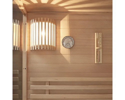 Interieur van een sauna met houten lambrisering, lamp, thermometer en hygrometer.