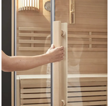 Hand opent saunadeur met glazen voorkant en houten frame