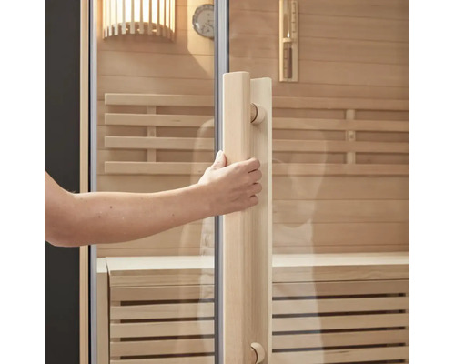 Een hand opent de deur van een sauna met houten elementen en een glazen voorkant
