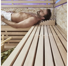 Man ontspant in een sauna met houten banken en accessoires.