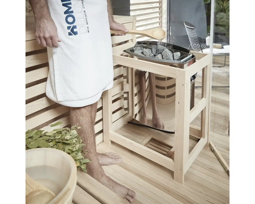 Saunascène met persoon, handdoek, houten lepel, stenen en saunakachel