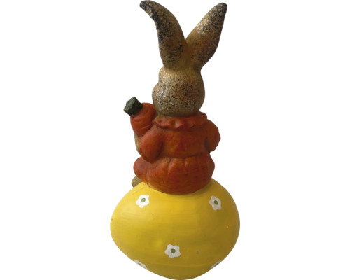 Decoratieve haas op een paasei met een wortel in de hand als tuindecoratie