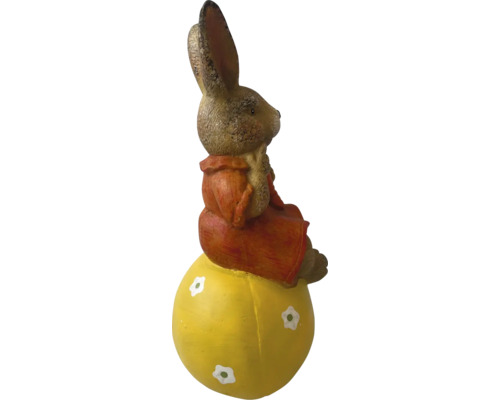 Paashaasfiguur zittend op geel ei als decoratie