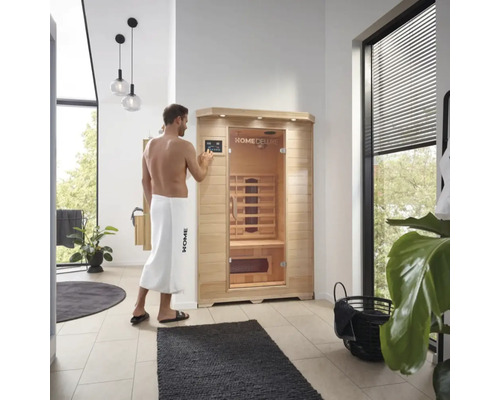 Man bedient een Home Deluxe infraroodsauna in een badkamer