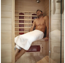 Man ontspant in een infraroodsauna met houten wanden en een glazen voorkant