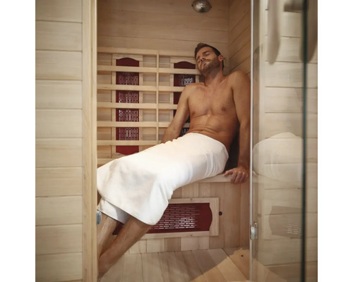 Man ontspant in een infraroodsauna met houten wanden en een glazen voorkant