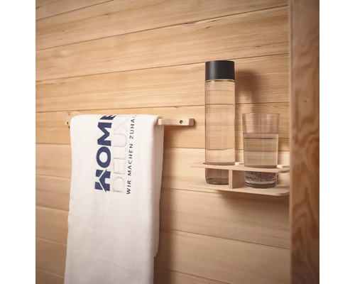 Handdoek aan handdoekhouder, drinkfles en glas op een plank voor een houten wand