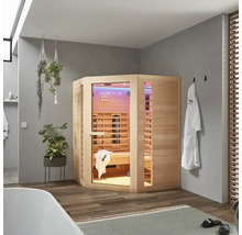 Houten infraroodsauna in een badkamer met bad, handdoeken en planten.