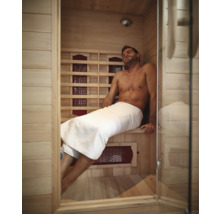 Man ontspant in een infraroodsauna met houten wanden en glazen deur