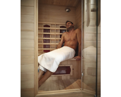 Man ontspant in een heldere houten infraroodsauna met glazen deur