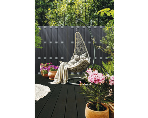 Hangstoel met kussens en deken op een terras met houten vloer en planten
