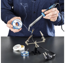 Persoon soldeert kabels met soldeerbout, soldeertin en soldeerpasta op een werkvlak.