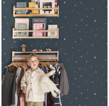 Kinderkamer met houten planken tegen een met sterren versierde muur en een jongen voor een kledingrek