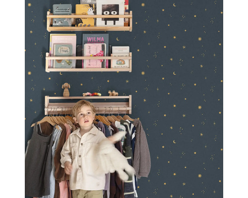 Kinderkamer met houten planken tegen een met sterren versierde muur en een jongen voor een kledingrek