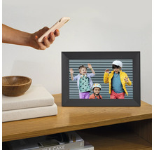 Digitale fotolijst op een houten plank met een foto van drie kinderen en een hand die een smartphone vasthoudt