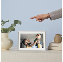 Digitale fotolijst met foto van een vader en zijn zoon op een tafel, naast een vaas met eucalyptus en een hand die naar de lijst wijst.
