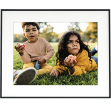 Zwarte fotolijst met witte passe-partout en een foto van twee kinderen in een weide.