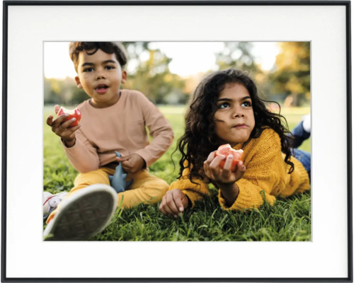 Zwarte fotolijst met witte passe-partout en een foto van twee kinderen in een weide.