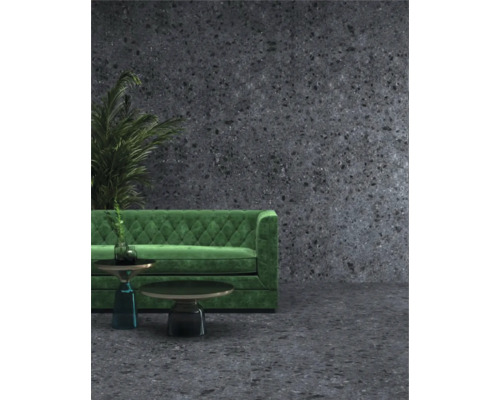 Scene met groene bank, twee tafels en een plant tegen een donkere muur met stippenpatroon.