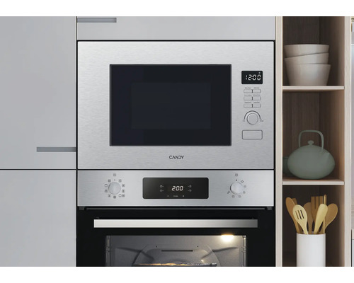 Moderne keuken met een Candy inbouwmagnetron en inbouwoven van roestvrij staal, geïntegreerd in lichte keukenkasten.