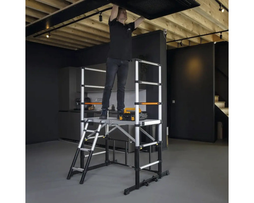 Man monteert plafondlamp op een aluminium rolsteiger in een kamer.